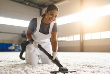 a woman vacuuming carpet in a warehouse